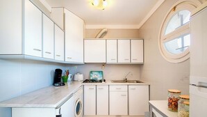 A compact kitchen with white cabinets, a washing machine, a sink, and a window. - Apartment with ocean views, a 10-minute walk from the waterfront (Roses)