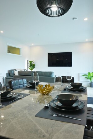A modern dining area with a marble table, black and gold dinnerware, and a black chandelier. - Le 102 Condo moderne au cœur de Magog (Magog)