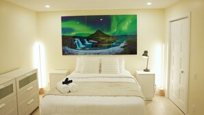 Ein Schlafzimmer mit einem Bett, einem Nachttisch, einer Lampe, einer Kommode und einem Bild des Polarlichts.