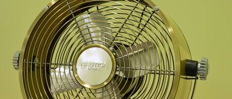 A vintage Nautica Home fan with a metallic finish, placed on a marble surface against a plain background.