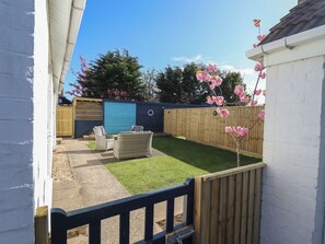 A backyard with a wooden fence, a blue shed, and a lawn. - Sorrento (Mablethorpe)