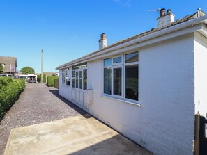 A white building with a paved pathway, large windows, and a chimney. - Sorrento (Mablethorpe)