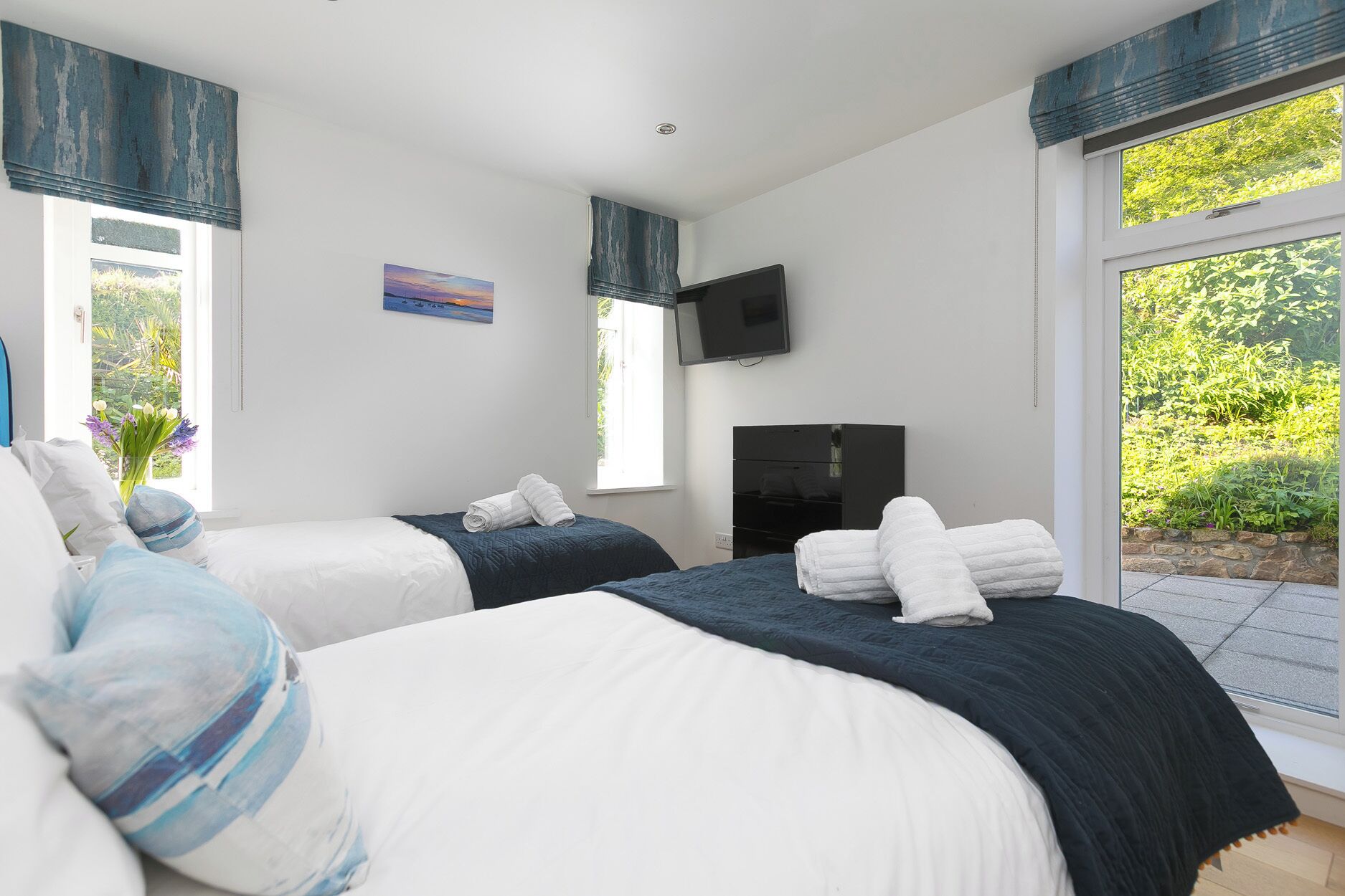 Une chambre d’hôtel avec deux lits, une télévision et une vue sur la verdure.