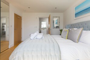 A bedroom with a bed, a headboard, a mirror, a bathroom visible through an open door, and a painting on the wall. - 2 Remera (St Ives)