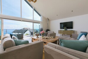 A spacious living room with a large window, a flat-screen TV, and a cozy seating area. - 2 Remera (St Ives)