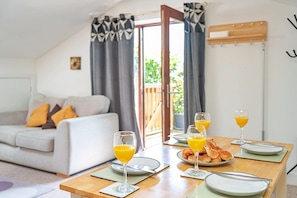 A dining area with a table set for breakfast, including plates, glasses, and croissants.