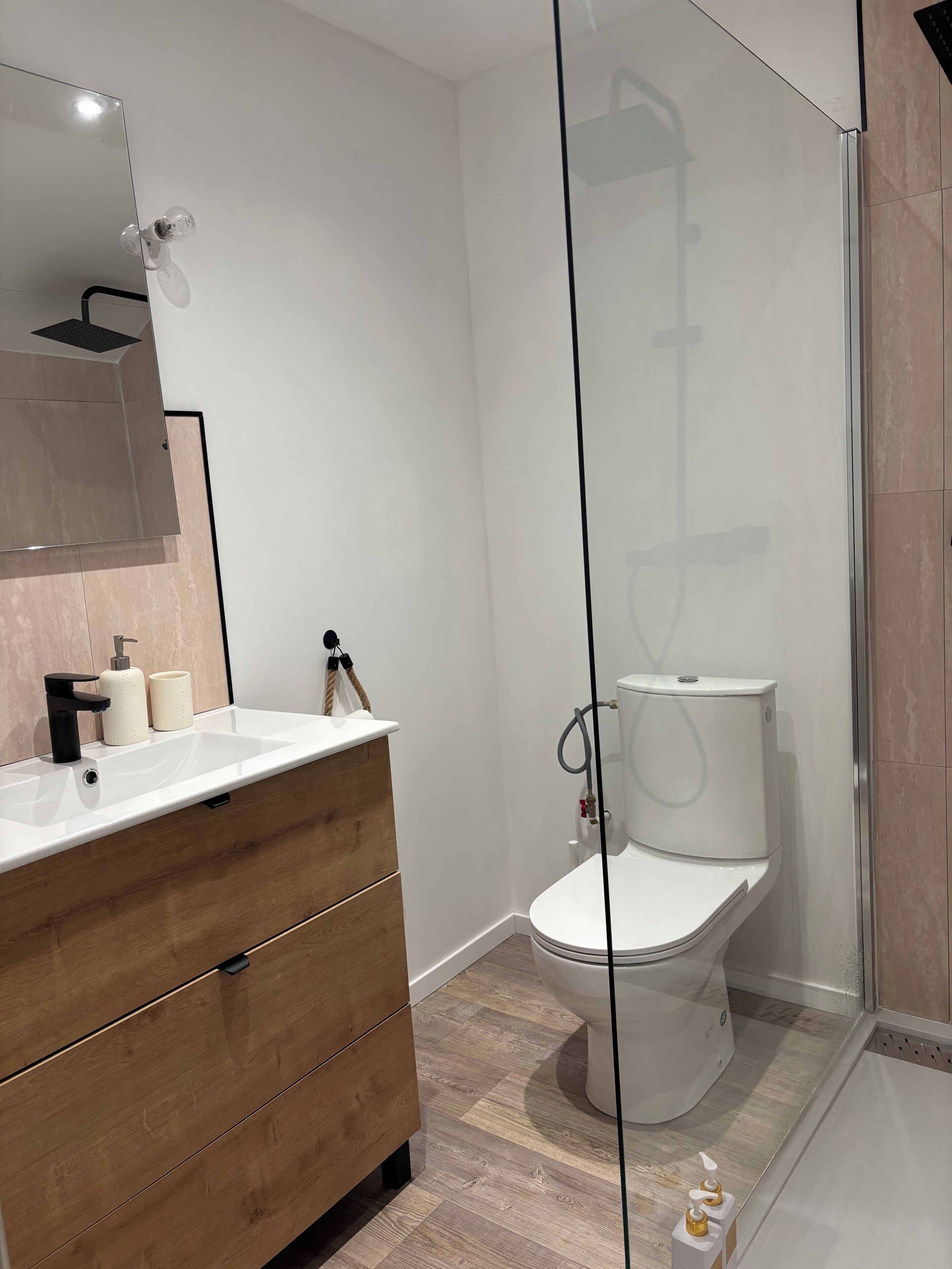Une salle de bain moderne avec un meuble-lavabo blanc, une cabine de douche en verre et des toilettes.