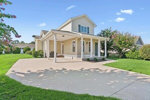 A two-story house with a covered porch, a lawn, and a driveway. - Pecan Pointe Cottage - Pet Friendly (Brunswick)