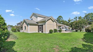 A two-story house with a covered porch and a well-maintained lawn. - Pecan Pointe Cottage - Pet Friendly (Brunswick)