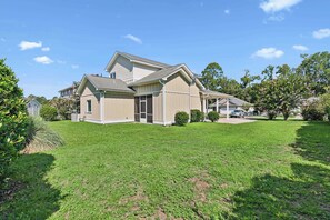 A two-story house with a covered porch and a well-maintained lawn. - Pecan Pointe Cottage - Pet Friendly (Brunswick)