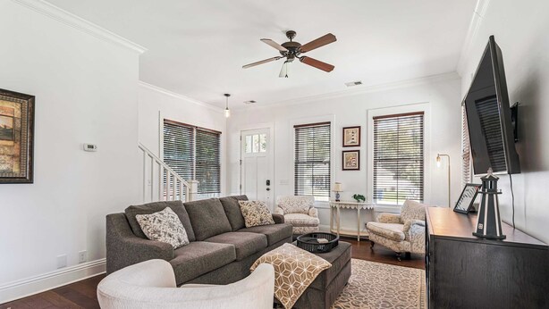 A living room with a sofa, armchair, ottoman, and a television. - Pecan Pointe Cottage - Pet Friendly (Brunswick)