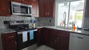 Una cocina con armarios de madera oscura, un microondas de acero inoxidable, una estufa y una ventana con vistas al exterior.