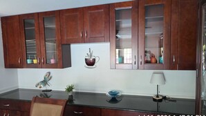 Una cocina con armarios de madera, un refrigerador, un adorno con taza de café, una planta y una lámpara.