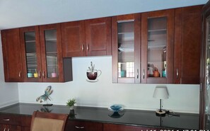 A kitchen with wooden cabinets, a refrigerator, a coffee cup decoration, a plant, and a lamp. - Charming 3-bedroom house with AC in terrific Sarasota (Sarasota)