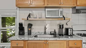 A kitchen with wooden cabinets, a stainless steel sink, a microwave, a toaster, and a coffee maker.