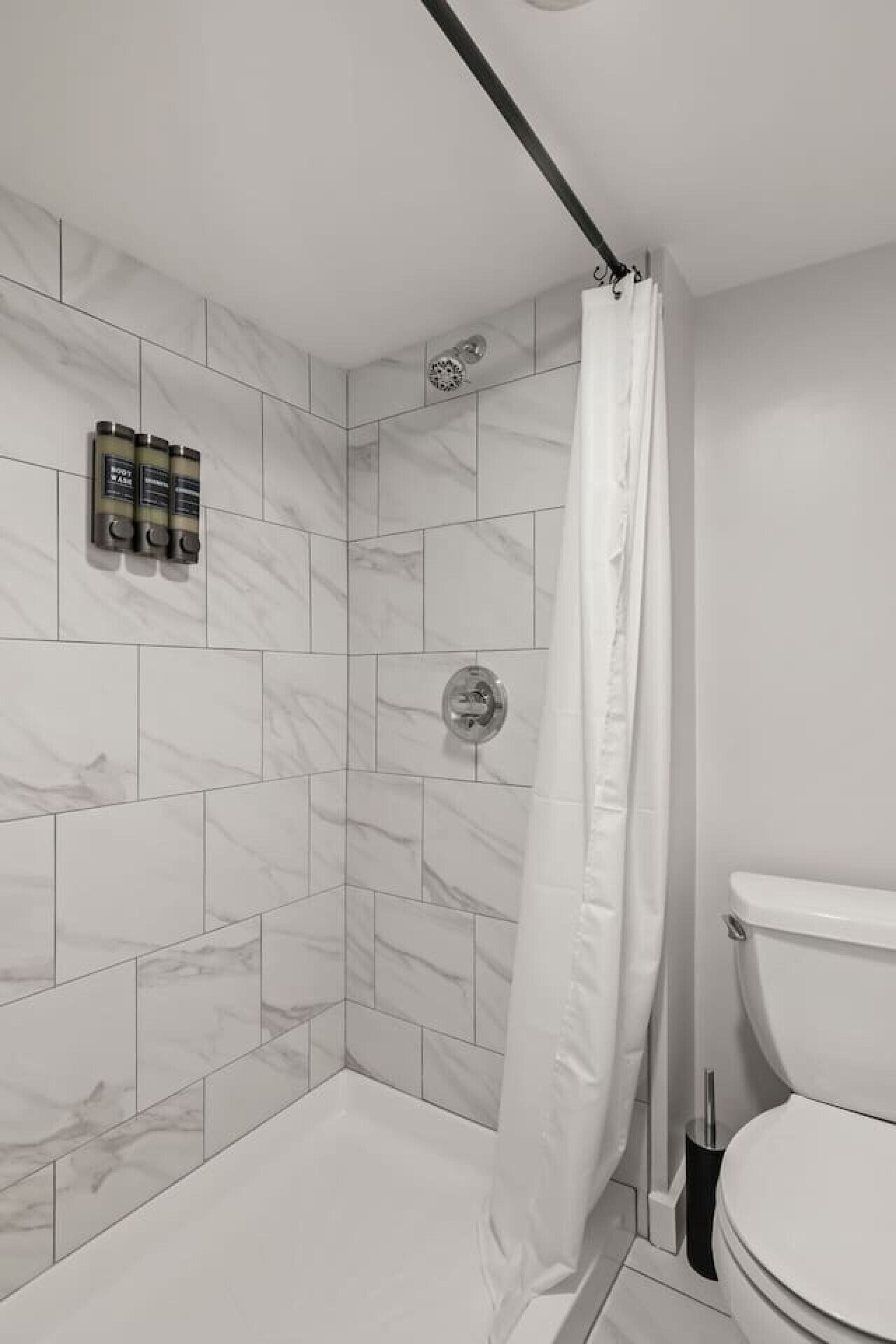 Une salle de bain moderne avec douche, toilettes et carrelage en marbre.