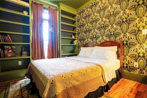 Une chambre à coucher avec un lit, une bibliothèque et un papier peint à motifs.