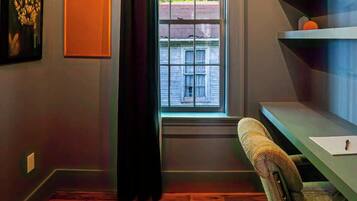 A room with a window, a chair, a rug, and a shelf.