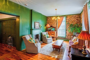 A room with a fireplace, two armchairs, a sofa, a coffee table, and a lamp.