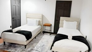 A room with two beds, a small table, and two doors. - Private Pool, Tennis Court, Outdoor BBQ Cozy Lodge (Loch Sheldrake)