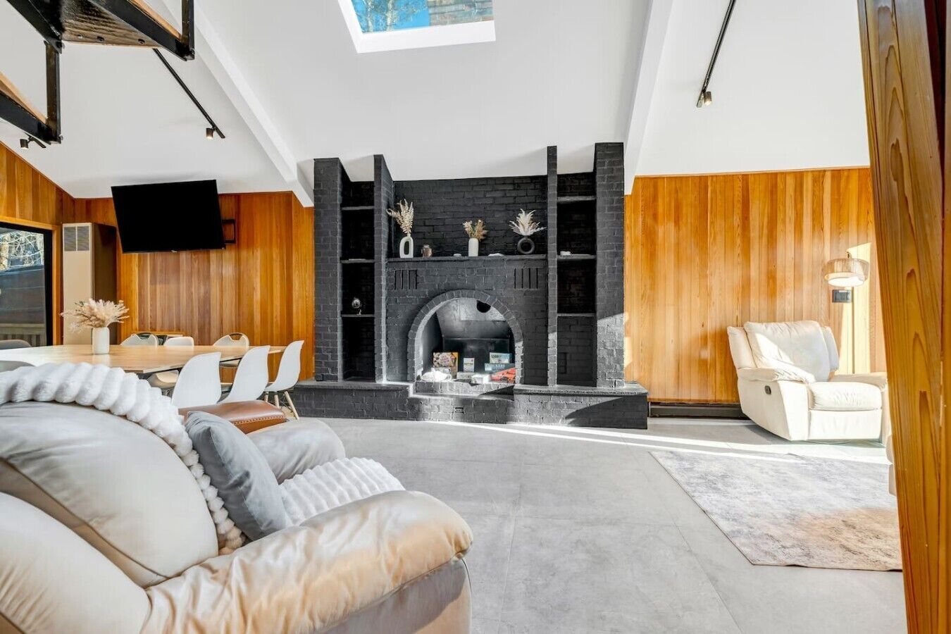 A modern living room with a fireplace, wooden paneling, a sofa, and a television.