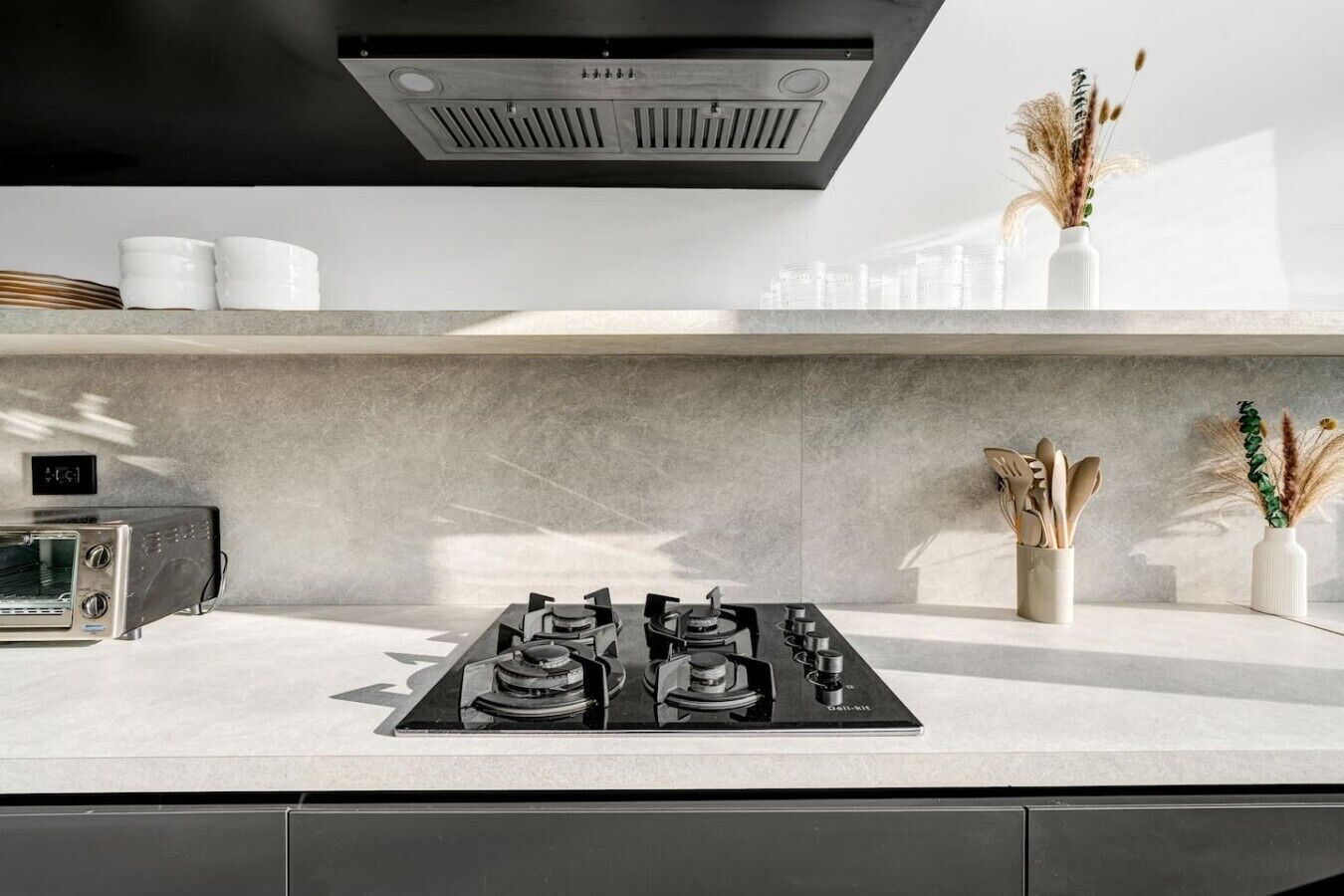 Een moderne keuken met een gasfornuis, een digitale klok en een broodrooster.