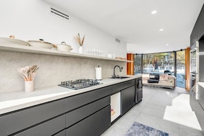 Uma cozinha moderna com uma ilha central, eletrodomésticos embutidos e vista para uma sala de estar.