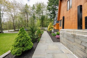 A modern house with a stone pathway, neatly trimmed hedges, and a variety of plants.