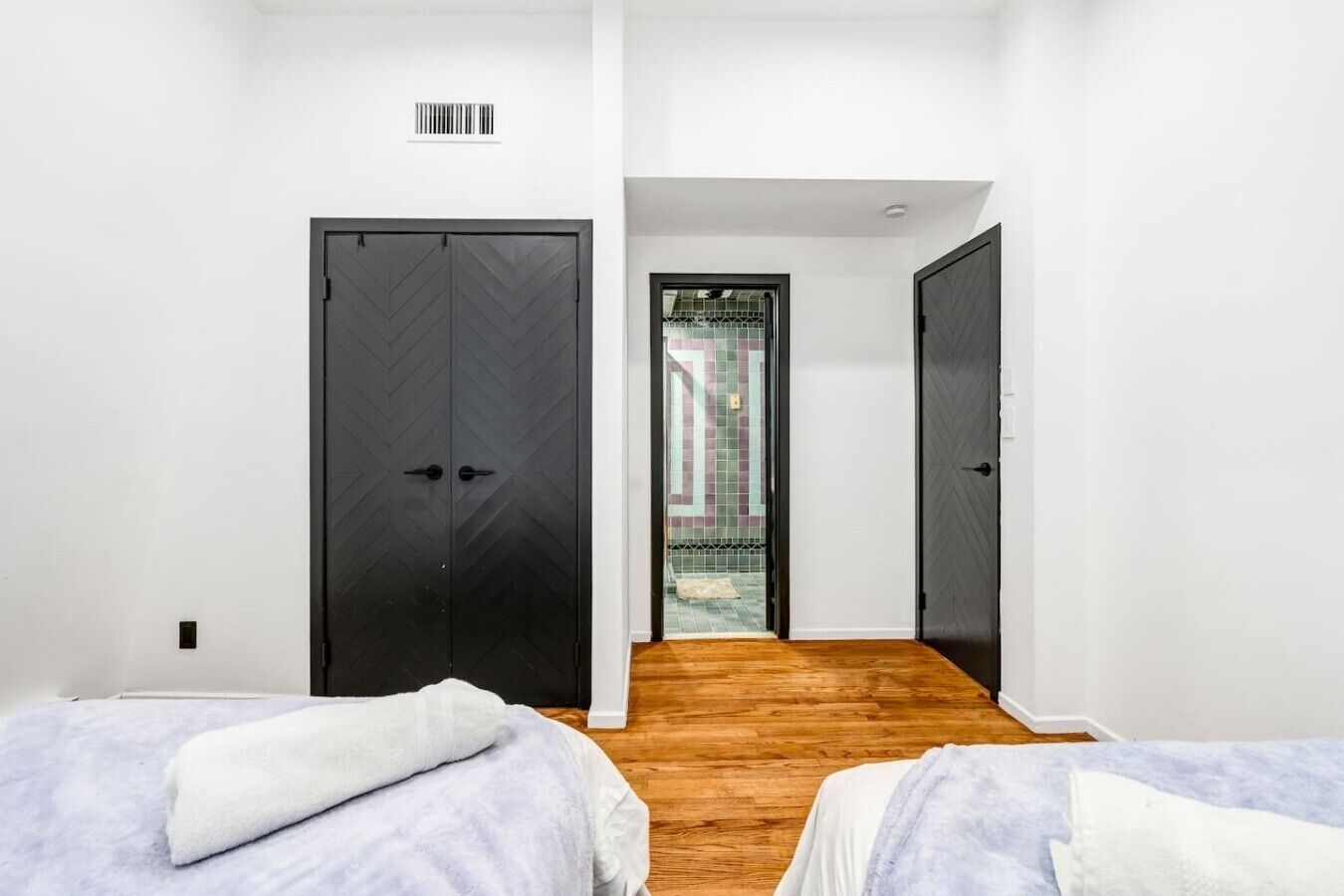 Un dormitorio con dos camas, suelo de madera y vistas a través de una puerta.