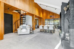 A spacious living area with a staircase, a dining table with chairs, and a fireplace.