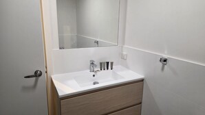 Une salle de bain avec un lavabo blanc, un miroir et un meuble en bois.