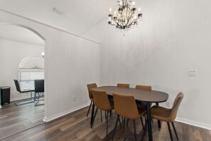 A dining area with a round table and six chairs, a chandelier, and a hallway with a curved ceiling. - Amazing 3/2 vacation home with private pool!! (Davenport)