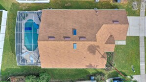 Ein Wohngebäude mit Schwimmbad, Ziegeldach und kleinem Garten.