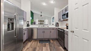 Eine moderne Küche mit Edelstahlgeräten, grauen Schränken und Holzboden.