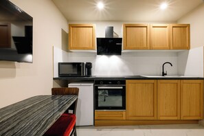 Een kleine keuken met houten kastjes, een magnetron, een oven en een spoelbak.