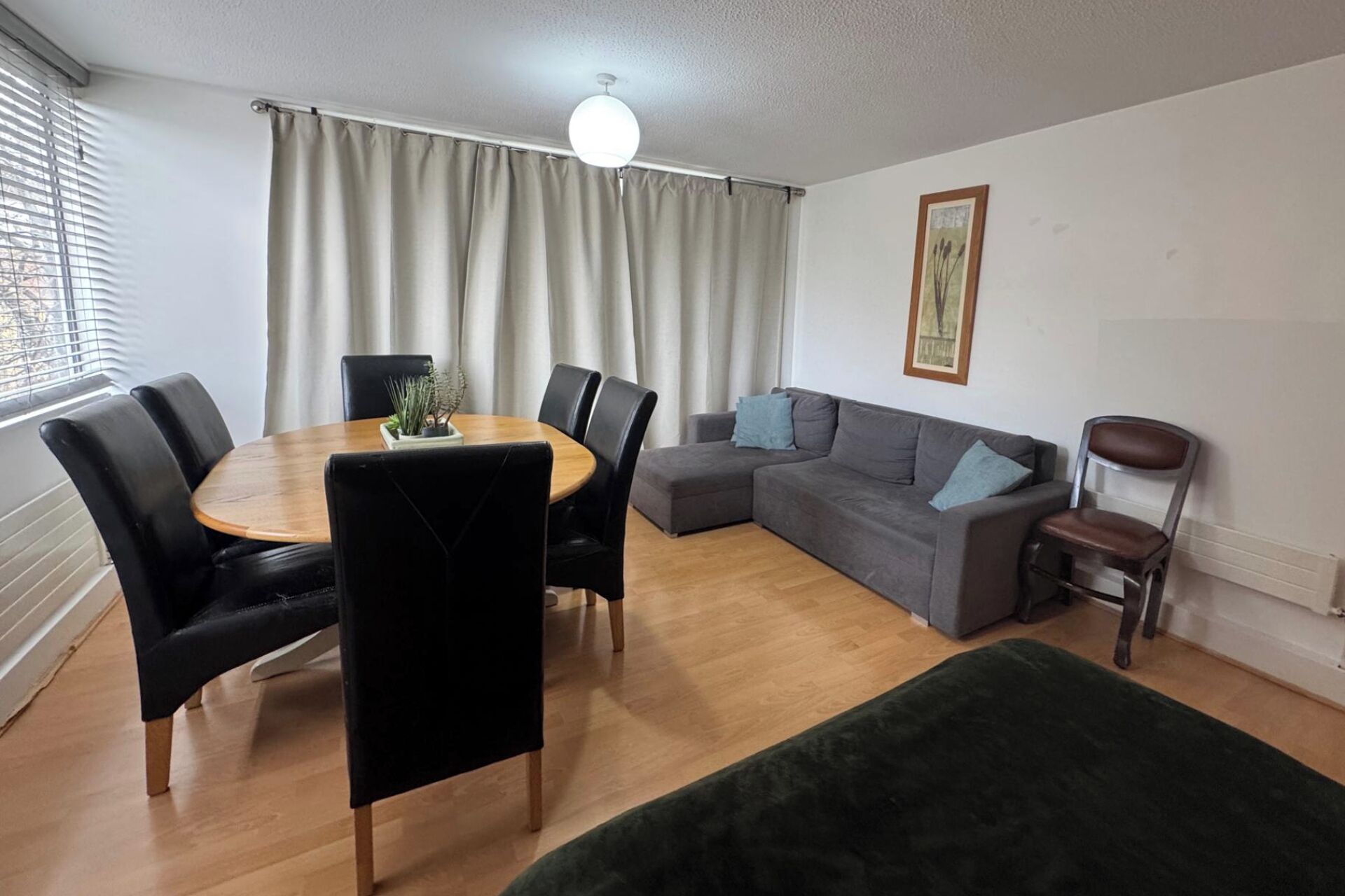 Un salon comprenant une table à manger, des chaises, un canapé et un pouf vert.