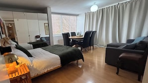 Een hotelkamer met een bed, een bureau, een stoel, een bank en een eettafel.