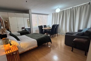 A hotel room with a bed, a desk, a chair, a sofa, and a dining table. - 4 Bedroom Apartment Sleeps 14 With Balcony (London)