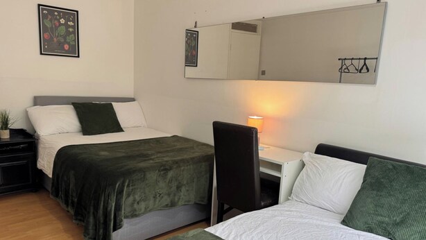 Een kamer met twee bedden, een bureau, een stoel, een lamp en een spiegel.