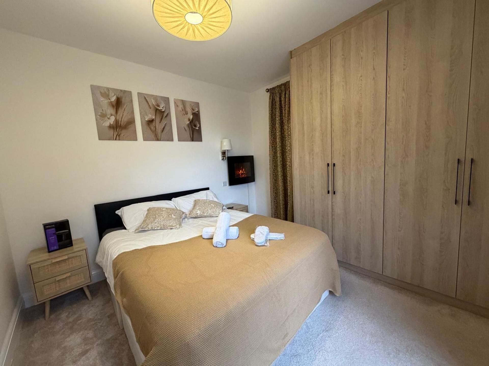 A bedroom with a bed, a nightstand, a TV, and a wardrobe.