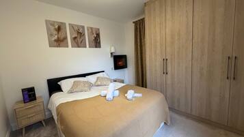 A bedroom with a bed, a nightstand, a TV, and a wardrobe.