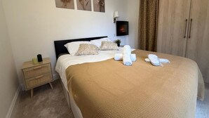 Une chambre à coucher comprenant un lit, une table de chevet, un téléviseur fixé au mur et une armoire.