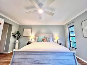 A bedroom with a bed, ceiling fan, bedside lamps, a window, and a potted plant. - Coastal Escape Near Sanibel, Pool, Lanai & Beach Adventures - Tropical Tides Townhome - Roelens (Fort Myers)