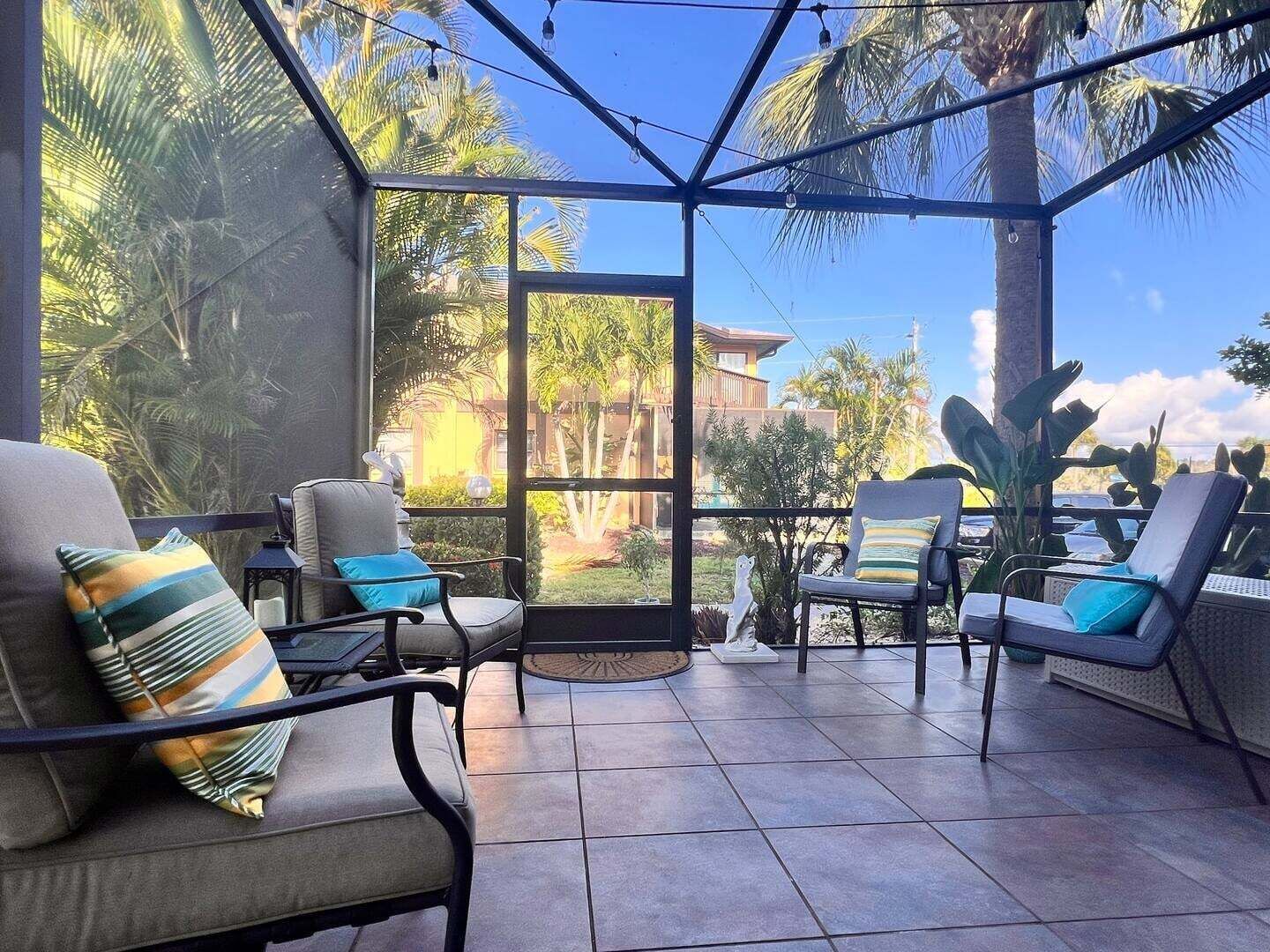 A covered outdoor seating area with chairs and a view of a residential building.