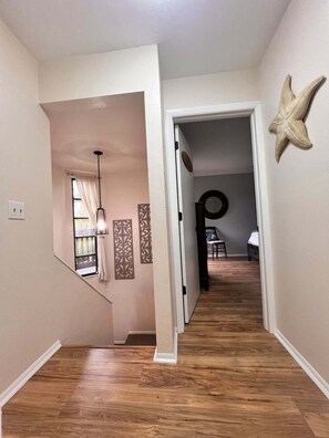 A hallway with wooden flooring, a starfish decoration, and a door leading to a bedroom. - Coastal Escape Near Sanibel, Pool, Lanai & Beach Adventures - Tropical Tides Townhome - Roelens (Fort Myers)