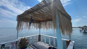 A wooden deck with a thatched roof, a bench, and a sign indicating a no smoking area.