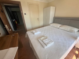 Una habitación de hotel con cama, armario, escritorio y puerta que da a un pasillo.