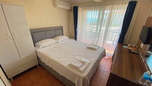 Una habitación de hotel con una cama, un armario, un televisor y un área de baño.