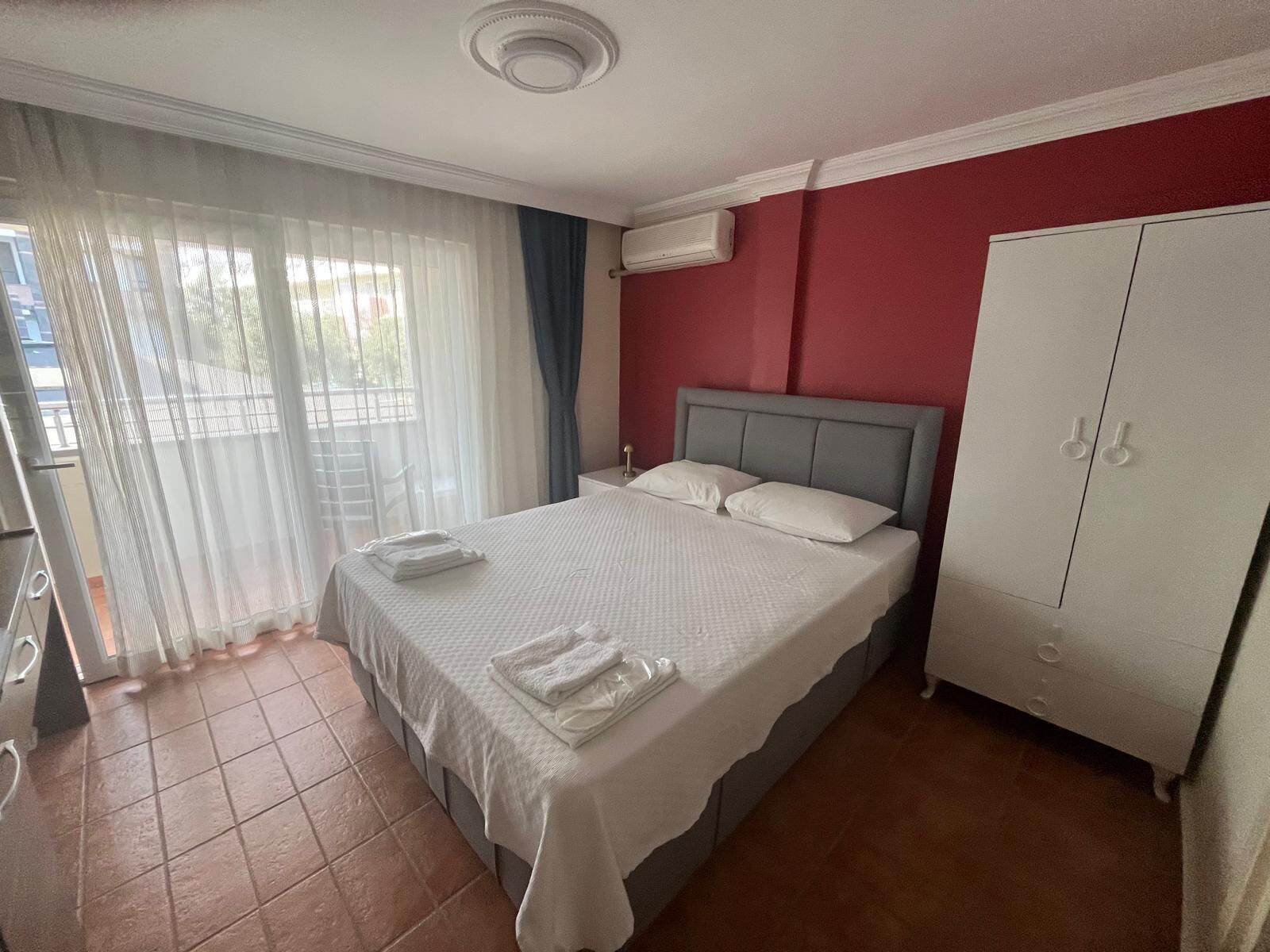 Una habitación de hotel con cama, armario y ventana con cortinas.