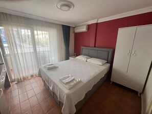 Habitació d'hotel amb un llit, un armari i una finestra amb cortines.